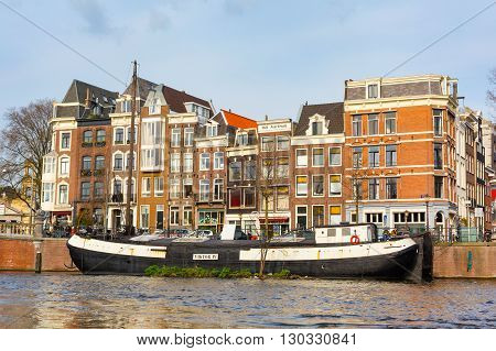 Amsterdam, Netherlands - April 1, 2016: Traditional old buildings canal and boat in Amsterdam, the Netherlands