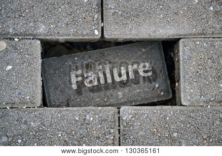 Word Failure written over a hole on the damaged pavement