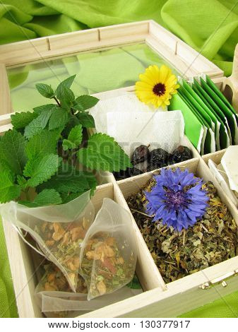 Tea box with loose tea, tea bags and fresh tea herbs