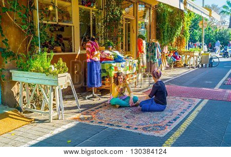 TEL AVIV ISRAEL - FEBRUARY 25 2016: The sellers from the clothes workshop sit cross-legged on the rug in market street of old Jaffa on February 25 in Tel Aviv.