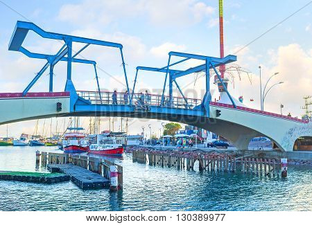 EILAT ISRAEL - FEBRUARY 23 2016: The modern drawbridge over the entrance to the marina with the yachts and pleasure boats on the background on February 23 in Eilat.