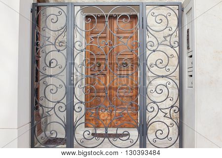 Iron gate the entrance to the arch in front of old house.