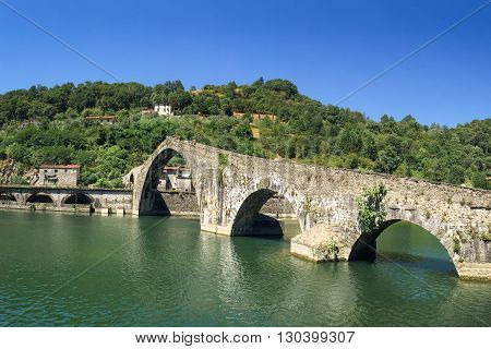 Unique Old Stone Bridge - the medieval Ponte Maddalena or Devils Bridge in Tuscany. Unrecognizable people at the crest of the bridge are included for scale.