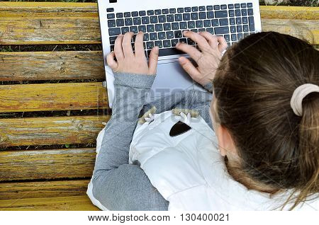 Girl with laptop sitting on a bench in the park