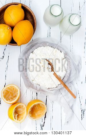 Soft homemade fresh ricotta cottage cheese made from milk draining on muslin cloth. Tzfat cheese with wheat grains. Symbols of judaic holiday Shavuot.