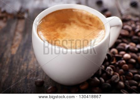 Cup of hot coffee with roasted beans on rustic wooden background