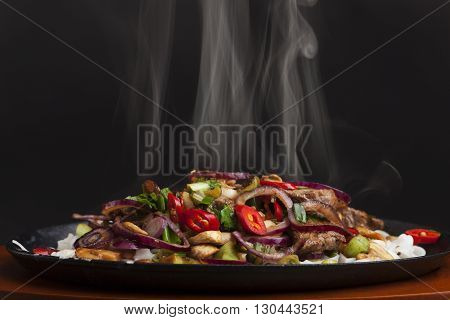steaming chicken sizzler with noodles on black