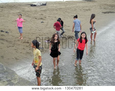 CEBU CITY, CEBU / PHILIPPINES - JULY 30, 2011: Children wade in the water at a beach in Cebu.