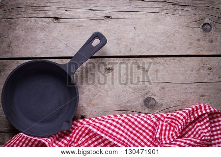 Empty frying pan on aged wooden background. Kitchen equipment. Selective focus. Place for text.