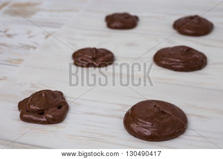 Unbaked chocolate Whoopie pies on white wooden bsckground