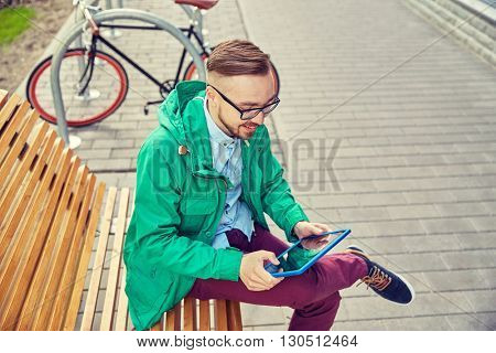 people, style, technology and lifestyle - happy young hipster man with tablet pc computer and fixie bike sitting on bench in city