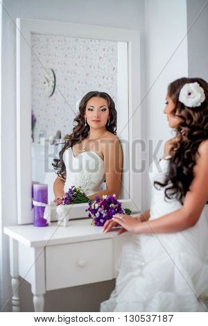 Happy and beautiful bride looks in the mirror