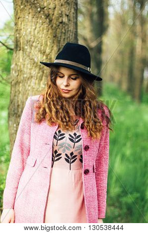 Portrait young elegant woman in pink coat and black hat. Fashion outdoors shot street style concept. Blogger outfiit. Spring portrait of stylish model posing in the park