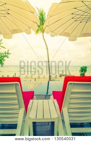 Beautiful beach chairs with umbrella around outdoor swimming pool neary sand and sea