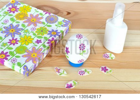 Decoupage Easter egg, glue, napkins with a floral pattern on a natural wooden background