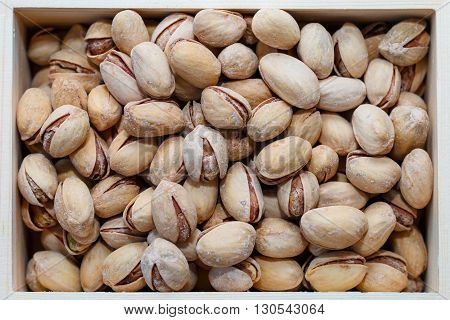 Pistachio nuts in a shell, salty, roasted in a wooden box