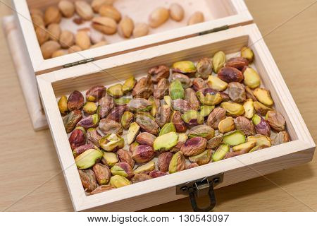 Green pistachio nuts without shell in a wooden box