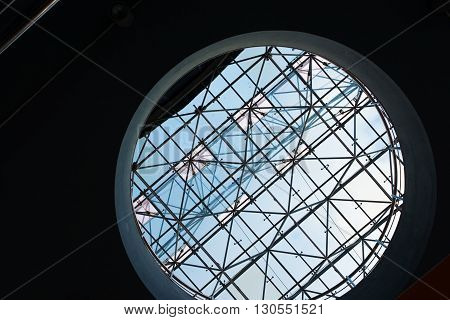 Bottom view of modern glass roof trough sircle hole in business district in evening light at sunset with copyspace.