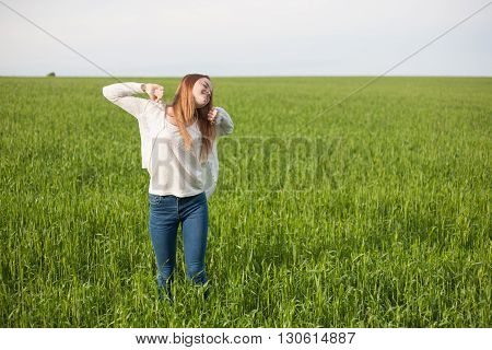 woman with open arms in the green wheat field at the morning.
