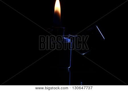 black gasoline lighter with flame on dark background