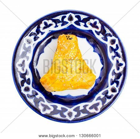 Traditional uzbek samsa bun with minced lamb. Served on authentic oriental plate. Isolated on a white background.