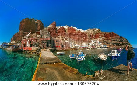 Photographer traveler takes pictures of Old port Amoudi of Oia village at Santorini island in Aegean sea, Greece