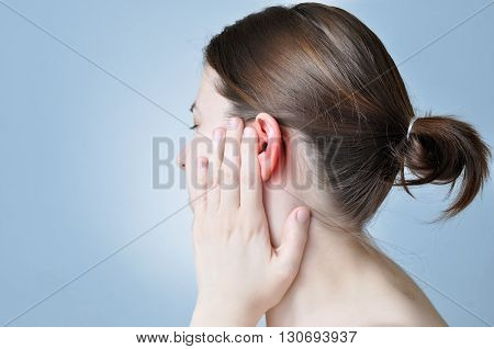 A young woman touching her inflamed ear