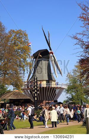 LISSE, NETHERLANDS - MAY 5, 2016: Tourists at the windmill in the Keukenhof Park in Lisse, Netherlands. It is popular flower garden which is visited by million tourists from all around world.
