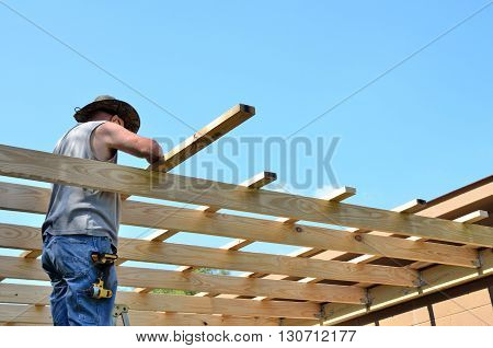 Man building roof add on too shop.  Active middle age senior working on DYI construction project