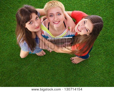 Three women with naked feet standing in grass .