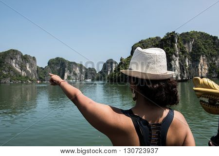 A tourist from the boat pointing with amaze towards the limestone karsts in Ha Long Bay, Vietnam. Ha Long Bay boats of thousands of limestone karsts like this and is a real treat to visit.