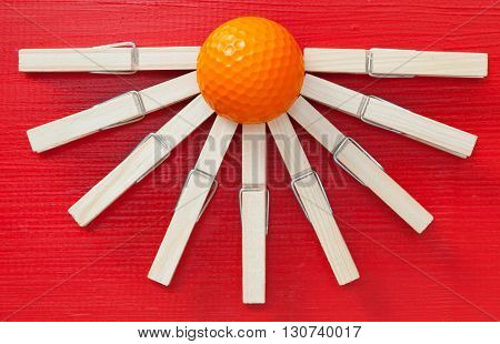 Set of cloth pegs and golf ball on wooden red table