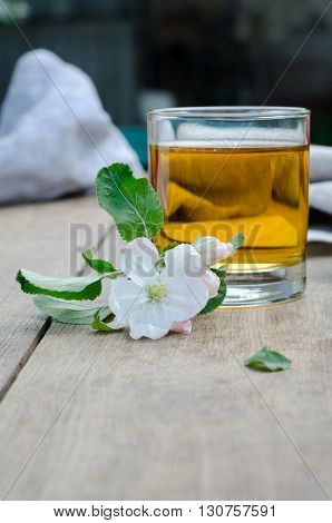 Apple juice and flowers of apple trees on a wooden table