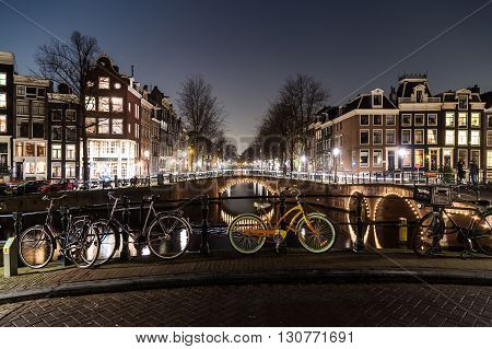 AMSTERDAM NETHERLANDS - 17TH FEBRUARY 2016: Bridges buildings and bikes at the Leidsegracht and Keizersgracht canal intersection in Amsterdam at night.