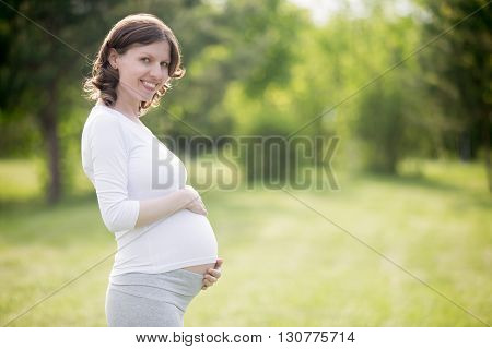 Happy Pregnant Woman On Late Pregnancy Stage Posing In Park