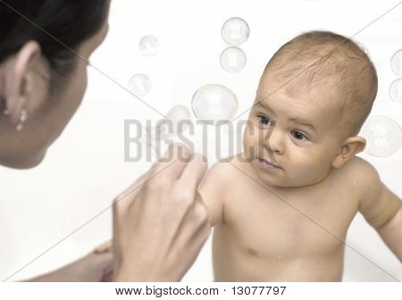 Ein Jahr altes Baby zusammen mit seiner Mutter spielt. Sie spielen mit Seifenblasen.