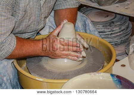 Clay on potters wheel using hands to create.