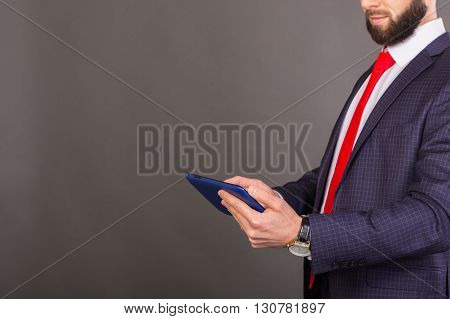 Young successful man in a business suit with a tablet in hands