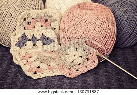 Crochet motives hook and cotton yarn on a blue background
