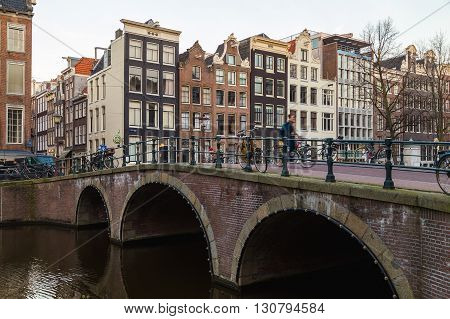 AMSTERDAM NETHERLANDS - 17TH FEBRUARY 2016: Bridges and buildings in the Centrum district of Amsterdam during the morning. A cyclist can be seen.