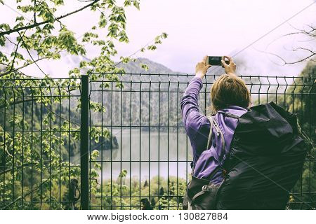Young Woman Traveler With A Backpack Taking A Photo With Smart Phone Mountain Lake. Caucasus, Abkhaz