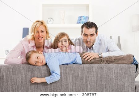Ritratto di coppia felice e due figli a casa, sorridendo.