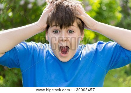 Teen boy screaming and holding his hands behind his head