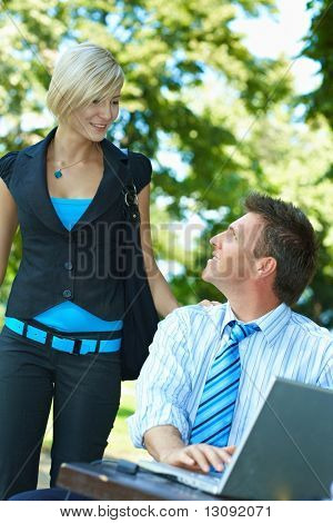 Casual uomo d'affari utilizzando laptopn nel periodo estivo del parco, mentre waitinf per la giovane donna, che appena arrivato