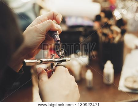 Make up artist filling the airbrush with liquid paint. Fading film colors