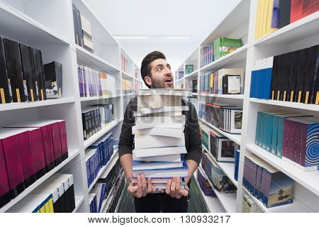 Student holding lot of books in school library. Hard worker and persistence concept.