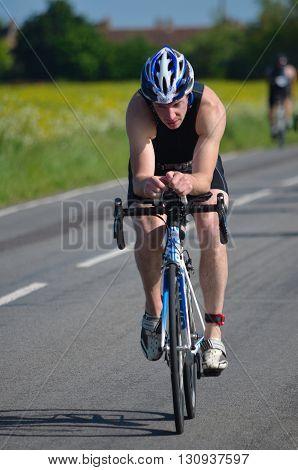 Grafham, Cambridgeshire, England - May 22, 2016:  Close up of Male triathlete on road cycling stage.