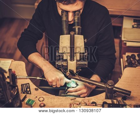 Jeweler looking at the ring through microscope in a workshop.