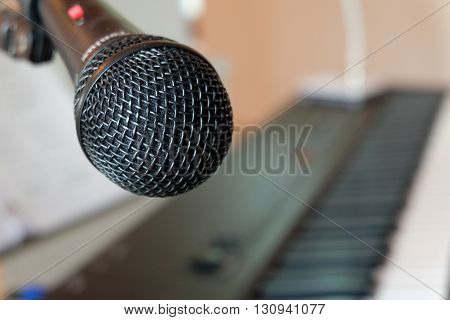 A close up microphone with a keyboard background