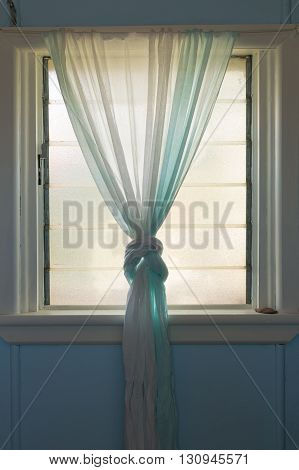 Light through pastel green curtins covering a window